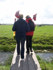 Wandelaars op loopbrug over sloot in weiland in wandelnetwerk Westfriesland