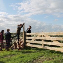 Wandelaars op overstap bij hek van boerenlandpad in wandelnetwerk Westfriesland